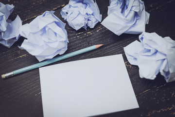 pencil on desk with notepad and scrunched paper balls
