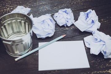 garbage bin on desk setting with pencil notepad and scrunched paper balls