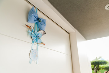 traditional blue stork hanging from door with ribbon and bow, in outdoors of house