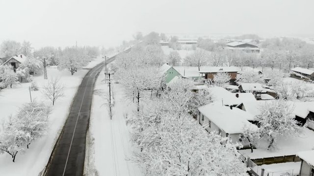 Drone 4K aerial footage of village covered with snow. White cloudy winter weather.