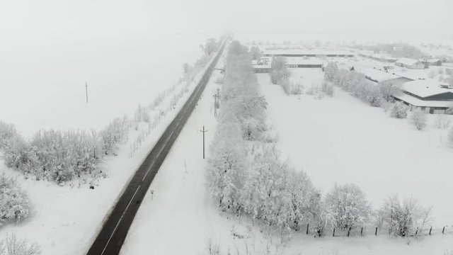 Drone 4K aerial footage of village covered with snow. White cloudy winter weather.