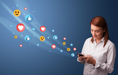 Young person using smartphone with flying social media icons around
