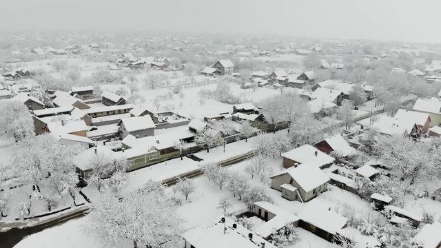 Drone 4K aerial footage of village covered with snow. White cloudy winter weather.