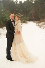 Naklejka premium two lovers in the forest, a happy couple, hugging, craving. smile, bride and groom. wedding in winter. suit and wedding dress. there will be snow,fog
