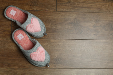cute women slippers with copy space for text. warm room slippers on a wooden floor.comfortable soft home shoes isolated on wooden background.home goods store