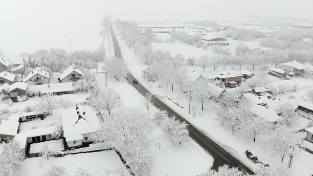 Drone 4K aerial footage of village covered with snow. White cloudy winter weather.