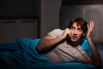 Young man talking on phone in bed