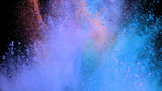 Super slowmotion shot of color powder explosions isolated on black background.