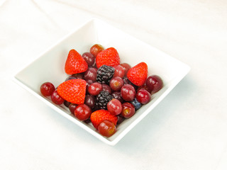 strawberries and plum in a square bowl