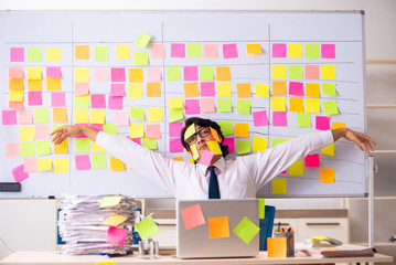 Young employee in conflicting priorities concept 