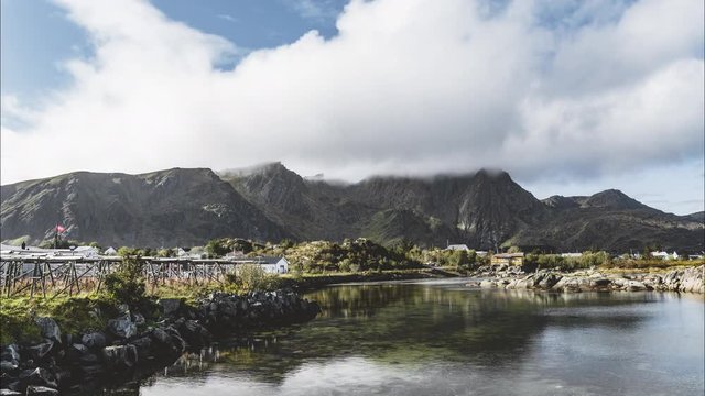 4k Timelapse movie film clip of village at Lofoten Islands in Norway on a blue sky with clouds sunny day and reflection in water.