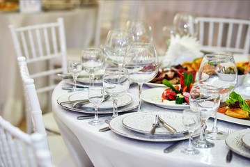 Elegant table setting in white beige tones ready for the arrival of guests. Beautiful dishes in restaurant interior