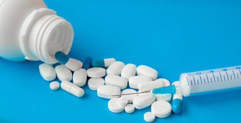 Assorted medical drugs and syringe on blue background, with copy space