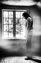 Fototapeta premium A sad man in front of window, grunge style