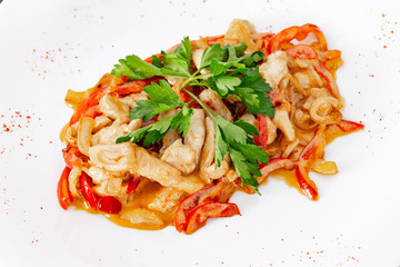 Chicken fricassee with mushrooms on a white plate with vegetables top view close-up
