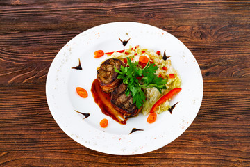 Juicy beefsteak minion from medium rare beef with a sauce on a white plate.