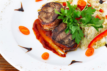 Juicy beefsteak minion from medium rare beef with a sauce on a white plate.