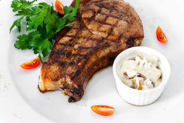 pork chop with vegetables in a white plate