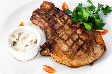 pork chop with vegetables in a white plate
