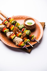 Chicken Hariyali kakab or Malai malai kebab served with skewers and yogurt dip in a plate. selective focus