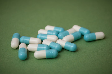 closeup of blue and white capsules and capsules on green  background