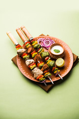 Chicken Hariyali kakab or Malai malai kebab served with skewers and yogurt dip in a plate. selective focus