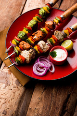 Chicken Hariyali kakab or Malai malai kebab served with skewers and yogurt dip in a plate. selective focus