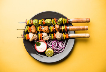 Chicken Hariyali kakab or Malai malai kebab served with skewers and yogurt dip in a plate....