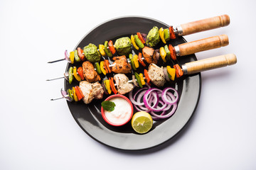 Chicken Hariyali kakab or Malai malai kebab served with skewers and yogurt dip in a plate....