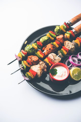 Chicken Hariyali kakab or Malai malai kebab served with skewers and yogurt dip in a plate. selective focus