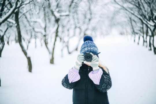 young girl photographer in the winter snowy park photographs nature.