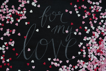 Flat lay on black chalkboard with hand lettered text message saying 'for my love' for Valentine's...