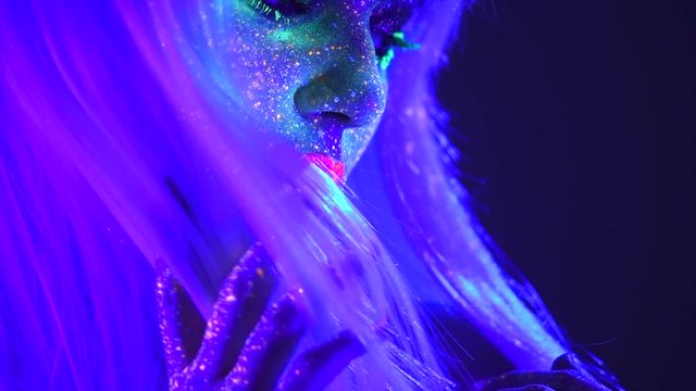Fashion model woman in neon light, beautiful model girl lips with colorful bright fluorescent makeup. Slow motion. 3840X2160 4K UHD video footage