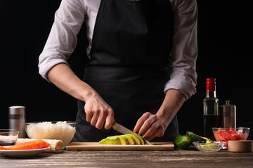 The chef cuts avocados for cooking Japanese sushi, rolls. The concept of delicious Japanese food, cooking, gastronomy, menus and recipe books