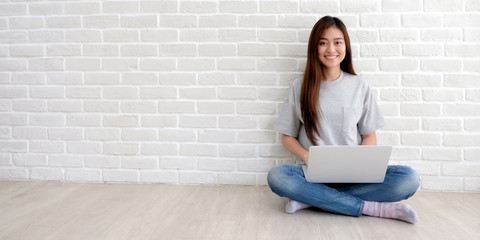 Young asian woman in casual style using laptop computer in white room background with copy space,...