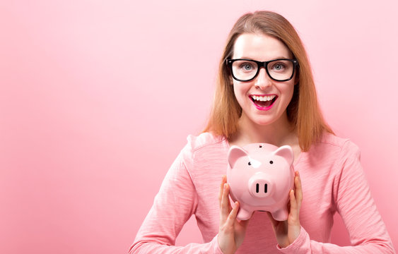 Young woman with a piggy bank on a solid background