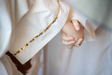 Children holding hands wearing white robes with gold trim