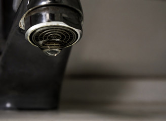 Leaking water drops from old rust and stained faucet