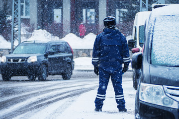 Traffic police dps on city street in winter.The snow is falling.
