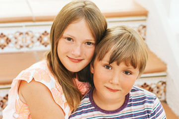 Outdoor summer portrait of two funny kids, small brother and big sister, siblings love