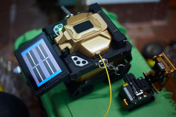 Fusion splicer machine on green case box. Fiber optic cable spliced by fusion splicer machine....
