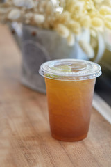 Lemon tea in plastic cup on counter bar table beside windows. Selective focus.