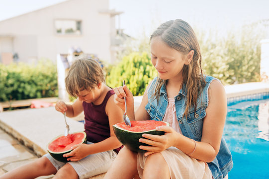 Outdoor summer portrait of two funny kids eating watermelon by the pool - Powered by Adobe