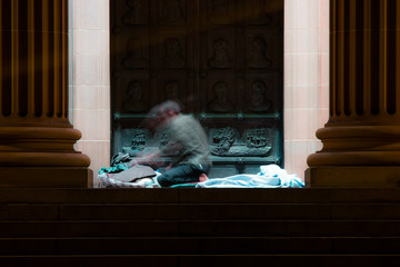 homeless man moves as he wakes on the steps of a city building