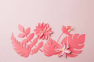 Fototapeta premium Handmade decorative paper pattern from tropical monochrome flower leaves on a pastel pink background with copy space. Top view. Live colar concept