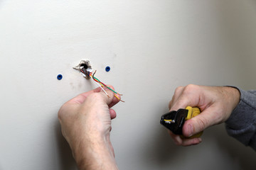 Close-up of Hand holding Wire for thermostat for air conditioning coming out of wall