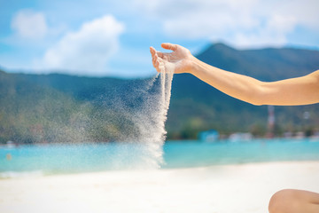 Beach trip vacation tropics concept, white sand strewed from female hands