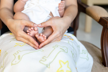 Newborn baby's feet on Mothers hand in heart shaped, Family and Love concept.