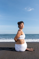 Fototapeta na wymiar Woman doing yoga exercices on a black beach