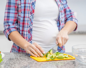 Close up pregnant woman preparing food at kitchen
